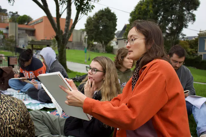 Natalie holding up her sketchbook while leading an outdoor urban sketching workshop in San Francisco.