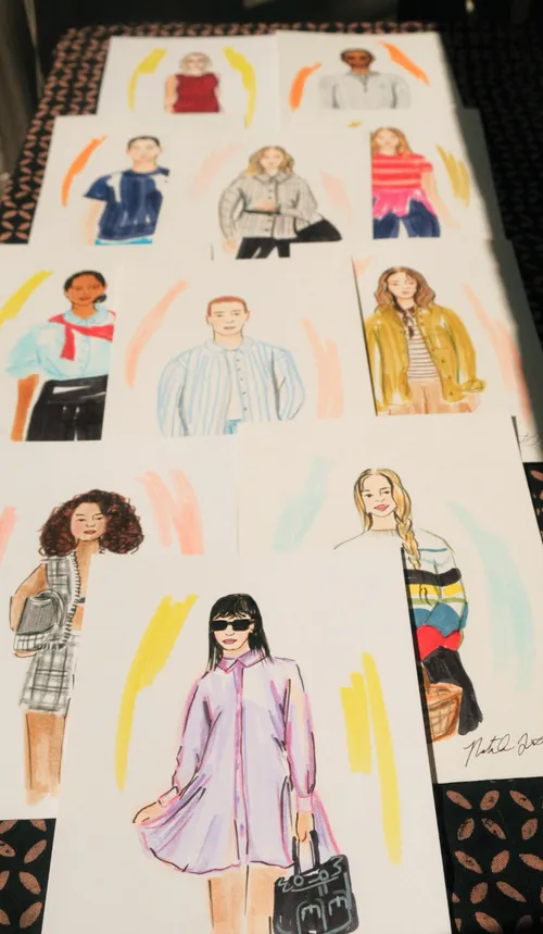 Colorful hand-painted guest fashion portraits arranged on a patterned table